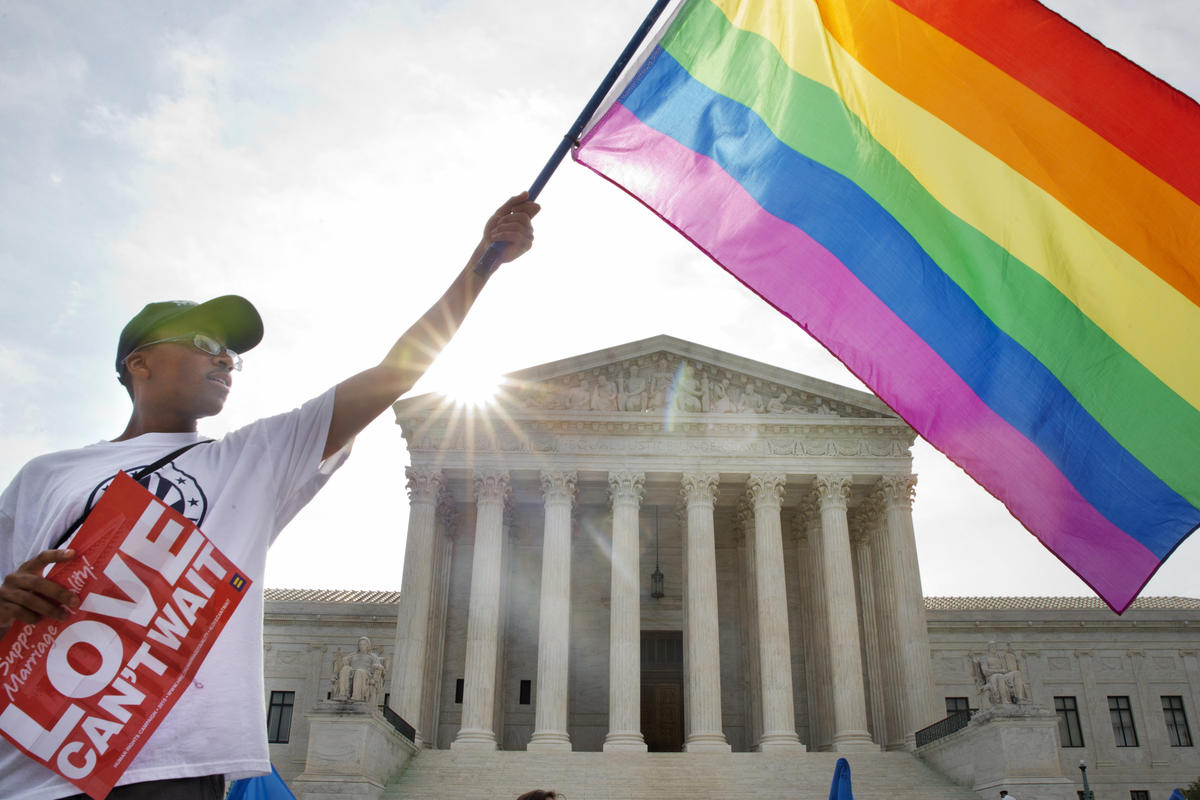 Carlos McKnight of Washington, waves a flag in support of gay marriage outside of the Supreme Court in Washington, Friday June 26, 2015.