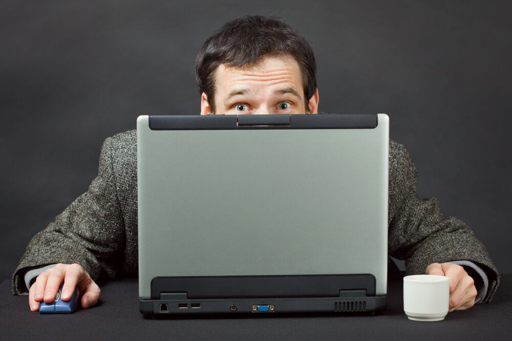 Man hiding behind laptop