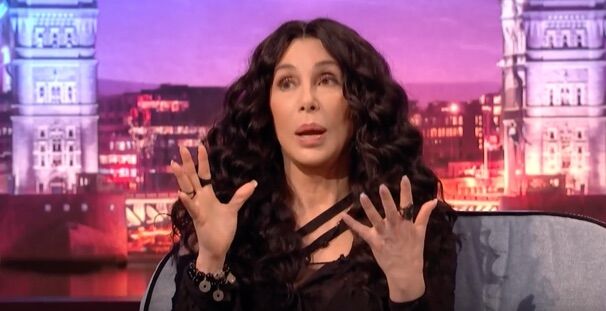 Cher gestures while talking to James Corden.