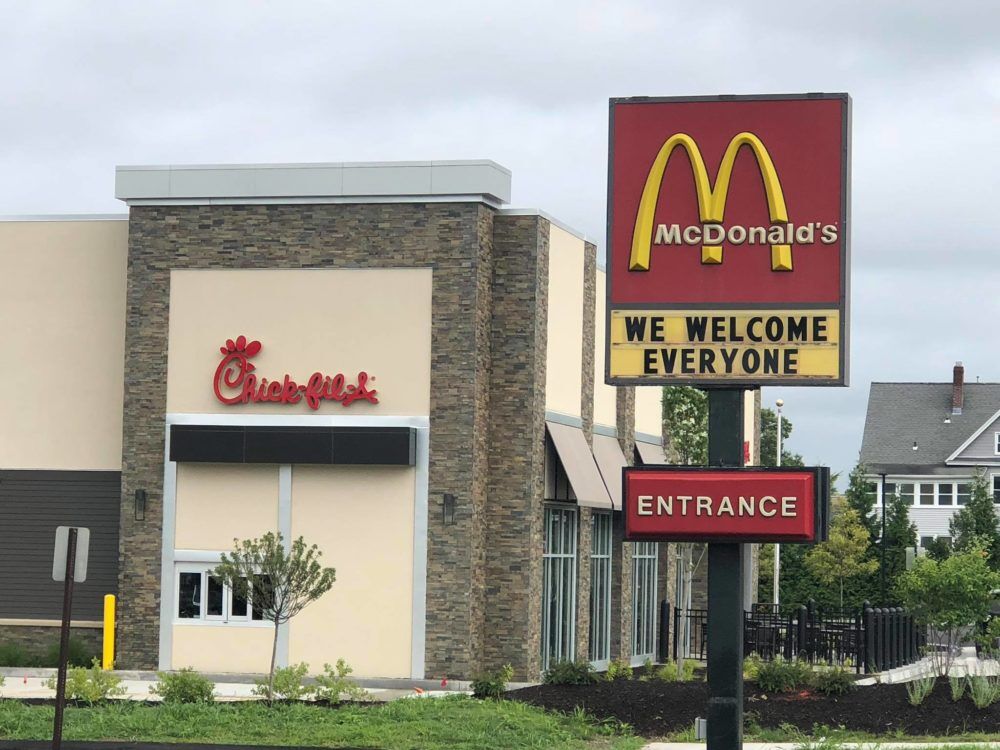 A McDonalds sign reading "We Welcome Everyone" with the soon-to-open Chick-fil-A behind it.