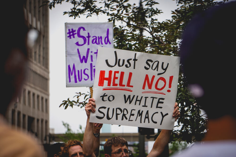 JUNE 26, 2018: Protestors hold signs that say "Just say hell no to white supremacy" to protest the supreme court's ruling on the muslim ban in Detroit, MI.