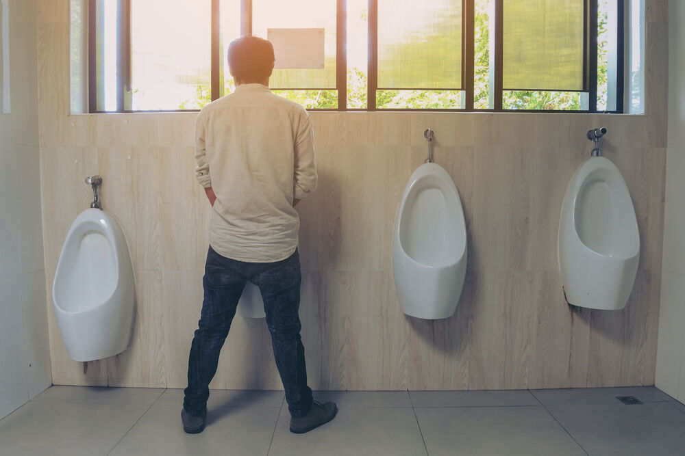 A man stands at a bank of urinals