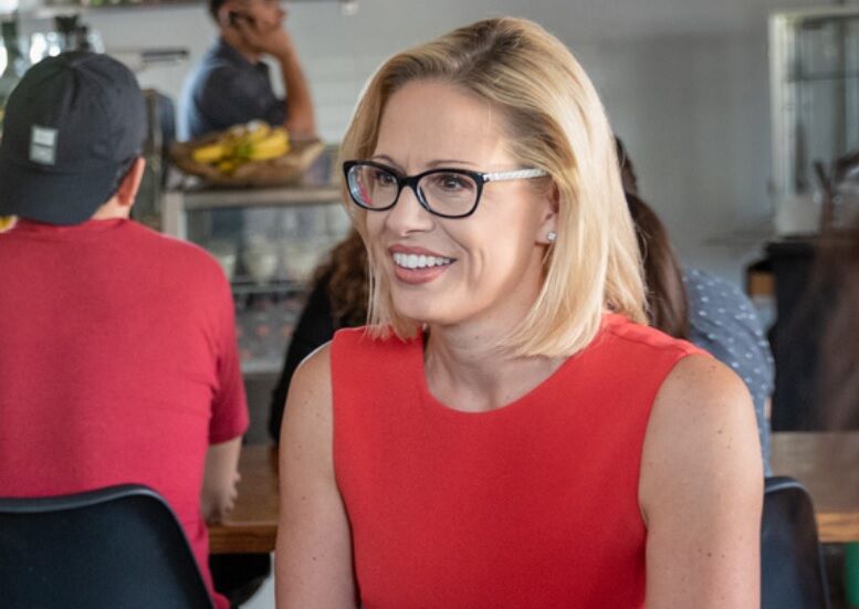 Kyrsten Sinema in a red blouse at a diner.