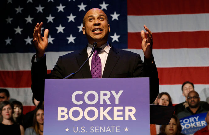 Cory Booker, in front of an American flag and behind a lectern bearing his name.