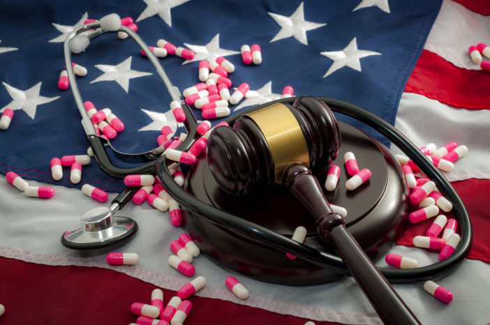 A gavel and a stethoscope and pills on top of an American flag