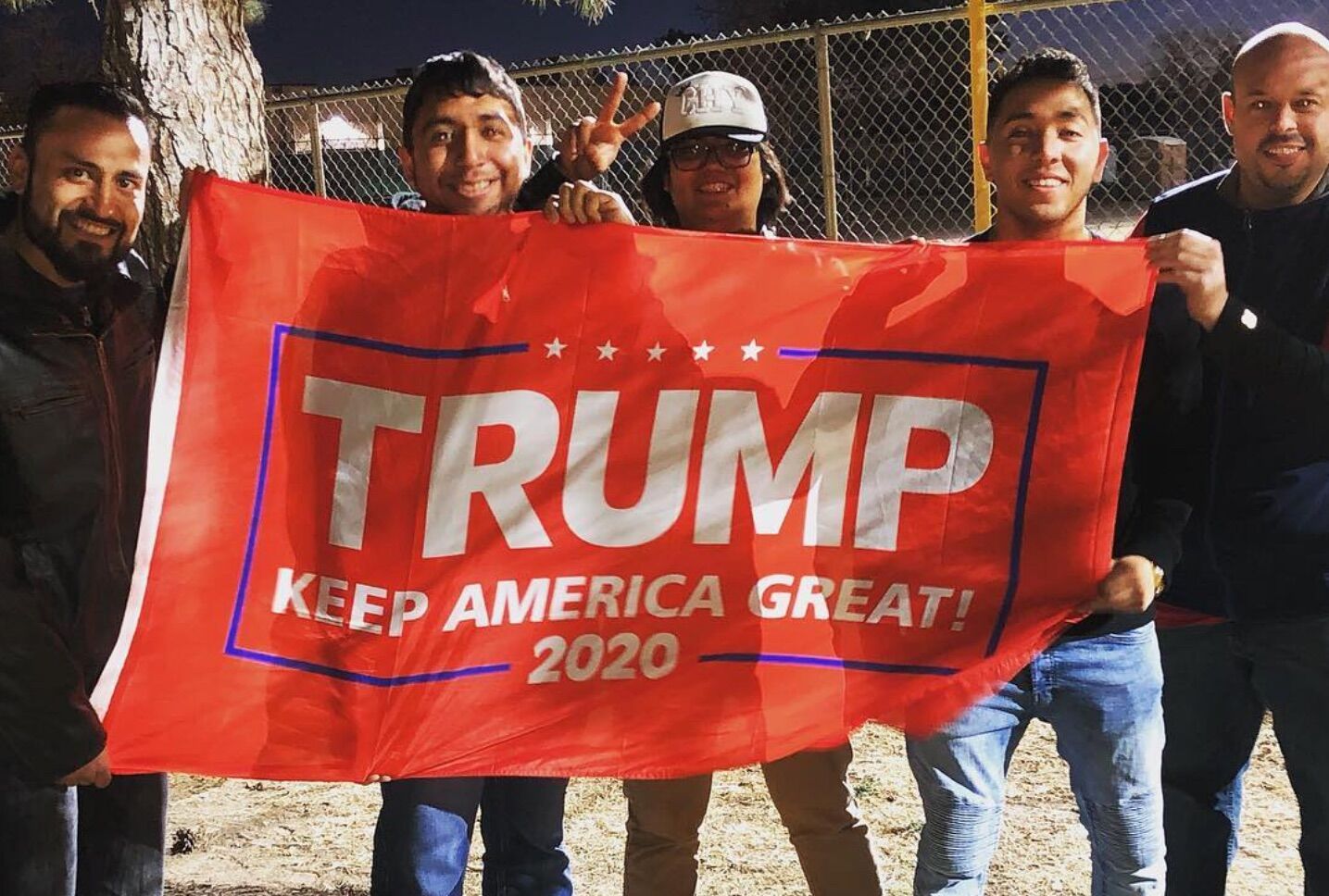 Johnny Alcantar poses with friends behind a banner during a Donald Trump rally in El Paso.