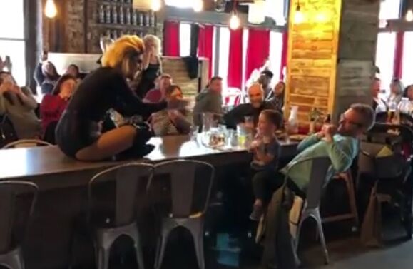 The drag queen on a table performing the song for the baby.