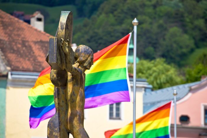 A crucifix in front of rainbow flags