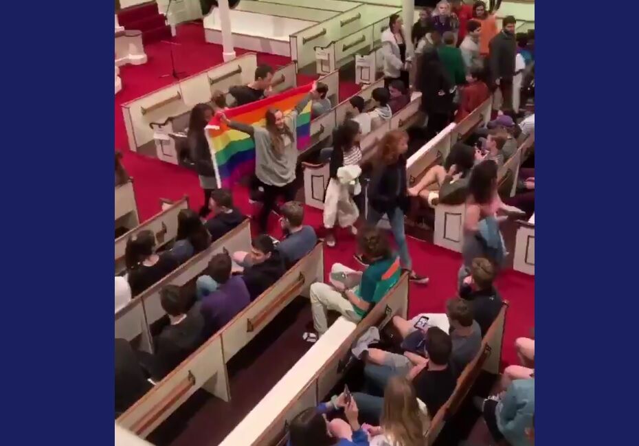 Students walking out holding a rainbow flag