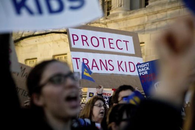 People protesting and a sign says "PROTECT TRANS KIDS"