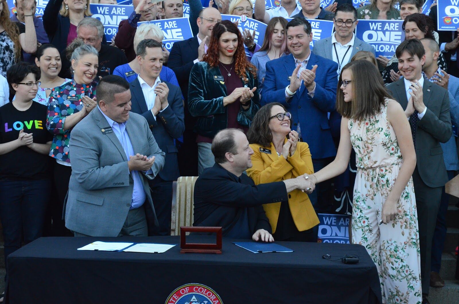 Governor Jared Polis hands the pen he used to sign Jude's Law to the legislation's namesake.