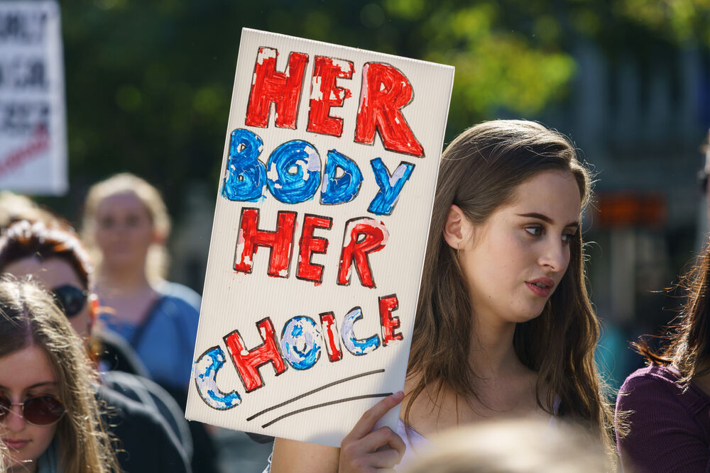 Woman holding a sign that says "Her body. Her choice."