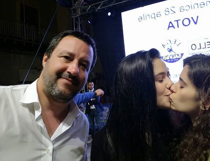 The two women kiss just next to a smiling Matteo Salvini