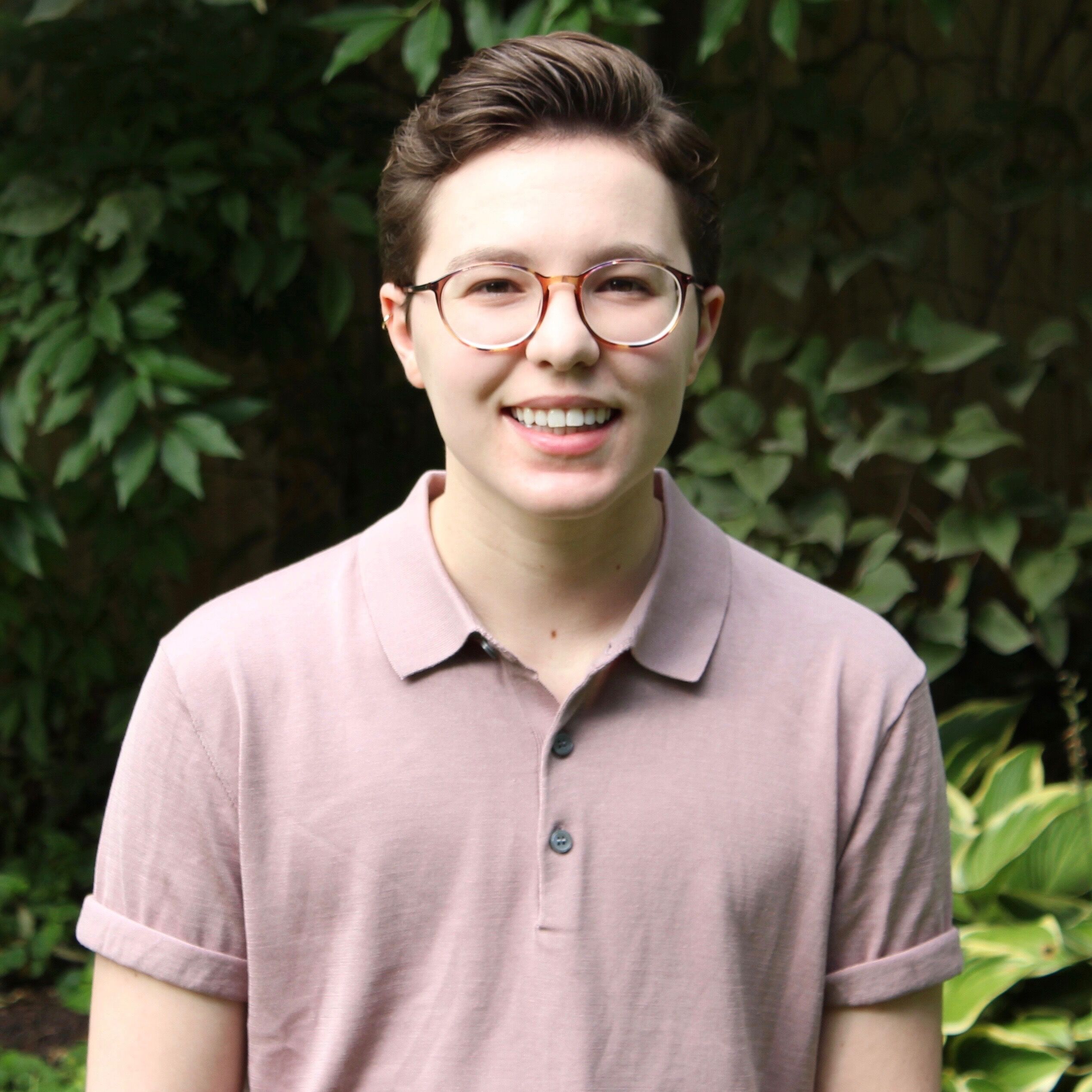 A headshot of Miranda Rosenblum, volunteer coordinator at The Trevor Project, in a beige collard shirt against a green backdrop.