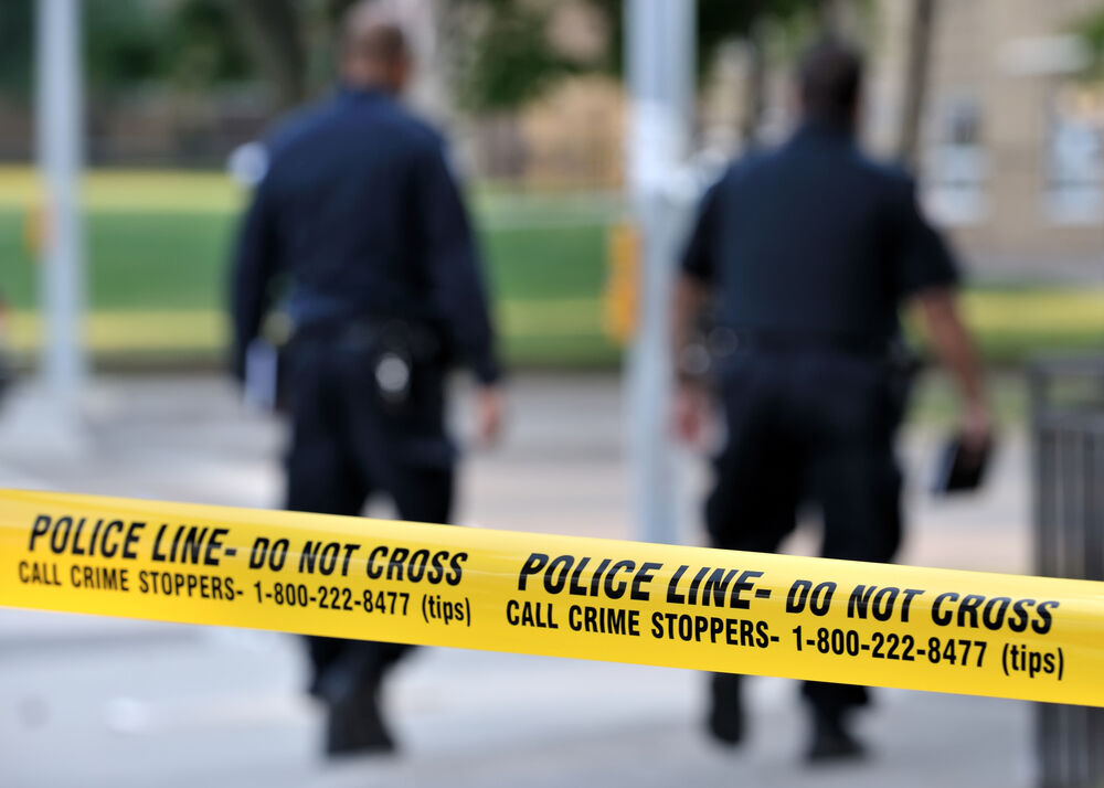 Two police officers behind police line tape.