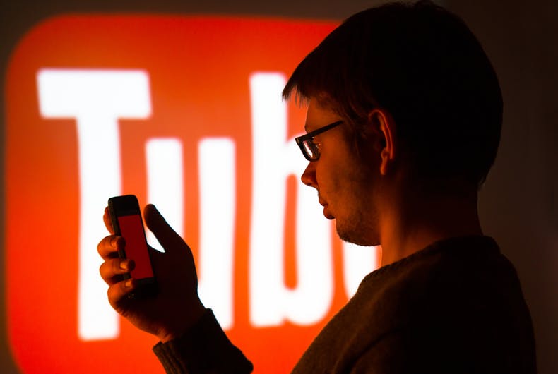 A person using their phone with the YouTube logo