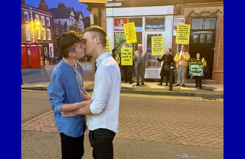 Joe Fergus and Robert Brookes kissing in front of the protestors.