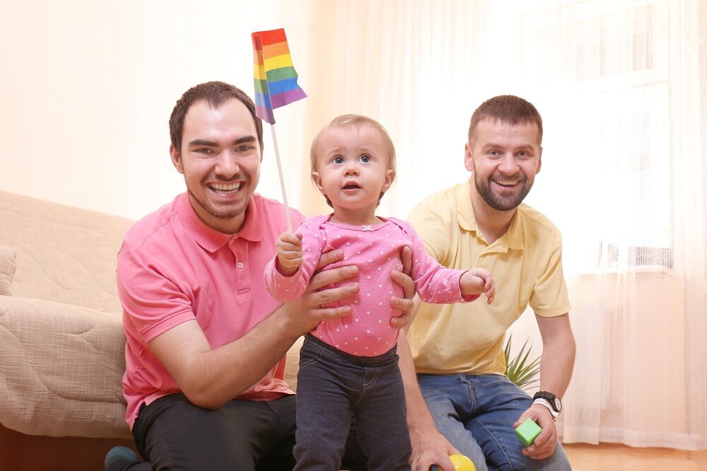 Gay couple with a baby and a rainbow flag