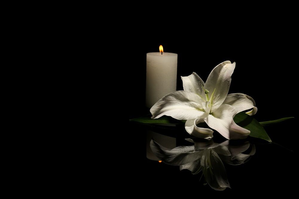 A candle and a lily, representing the concept of mourning