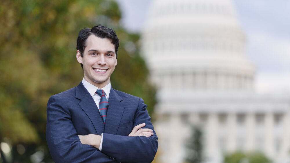 A man in a suit smiles in front of the U.S. Congress building