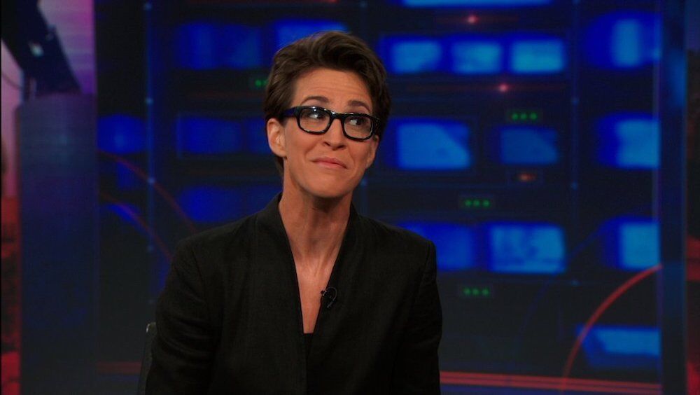 Rachel Maddow, a lesbian newscaster in horn rimmed glasses, grimaces while on "The Daily Show"