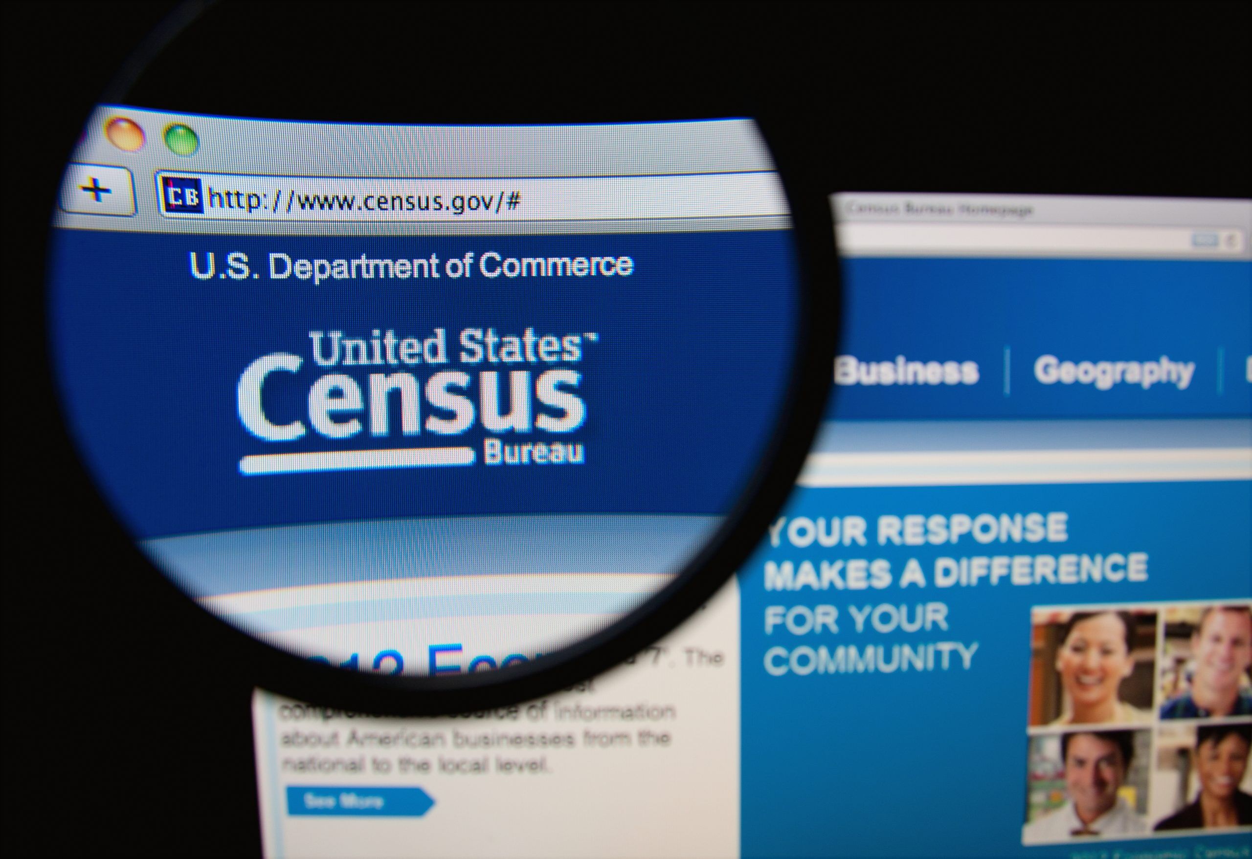 Photo of the United States Census Bureau homepage on a monitor screen through a magnifying glass.