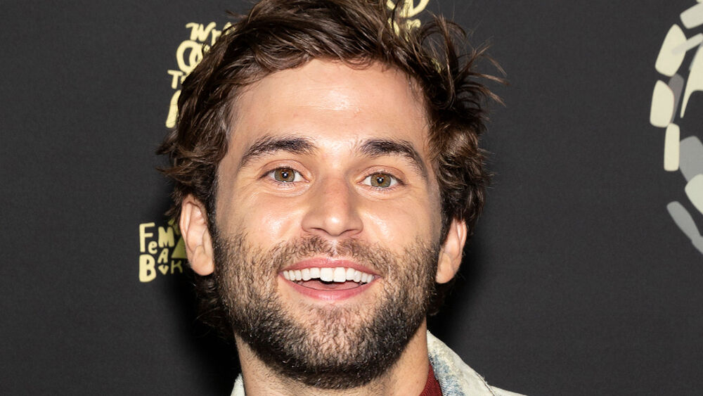 Jake Borelli smiles at a red carpet event