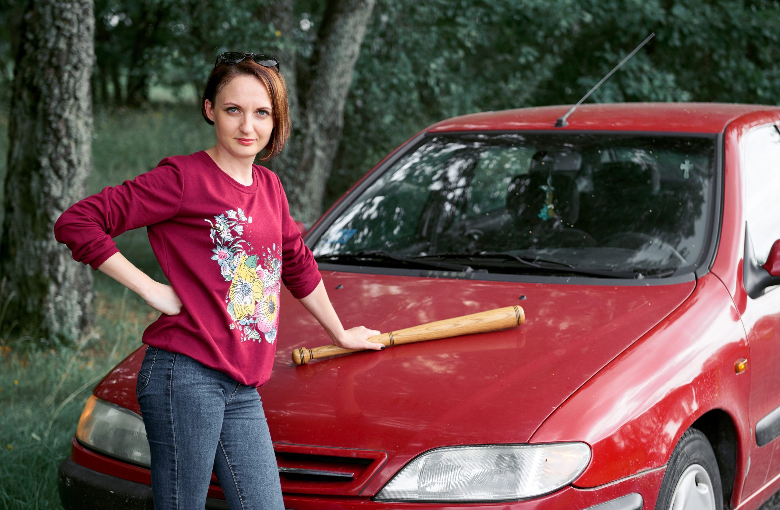 Woman with a baseball bat on a car
