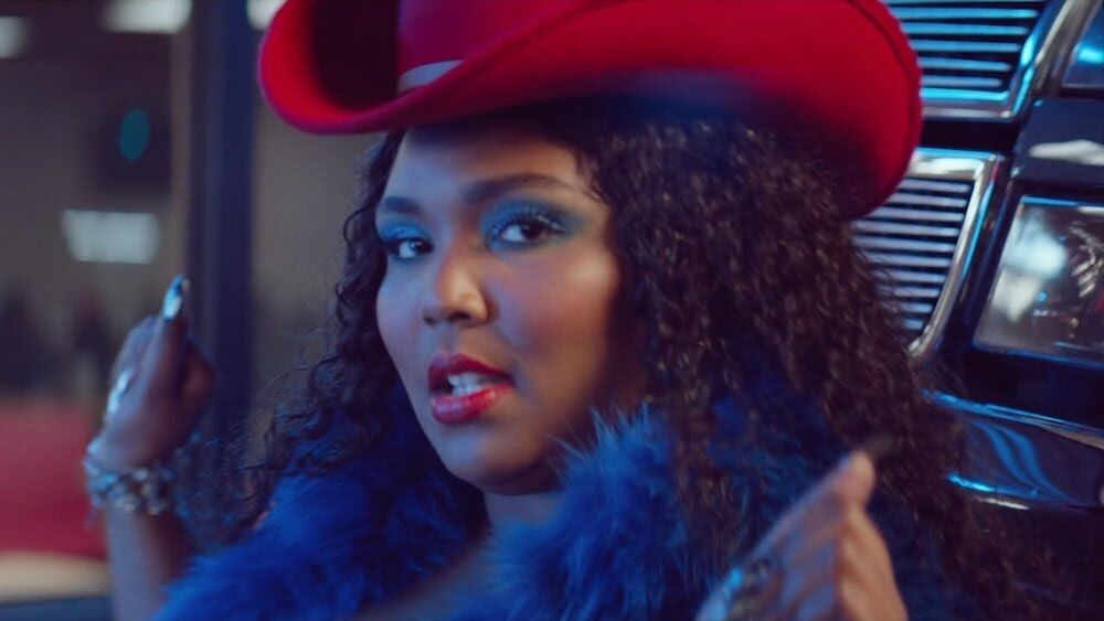 Lizzo wears a boa and a cowboy hat in her video for "Tempo"