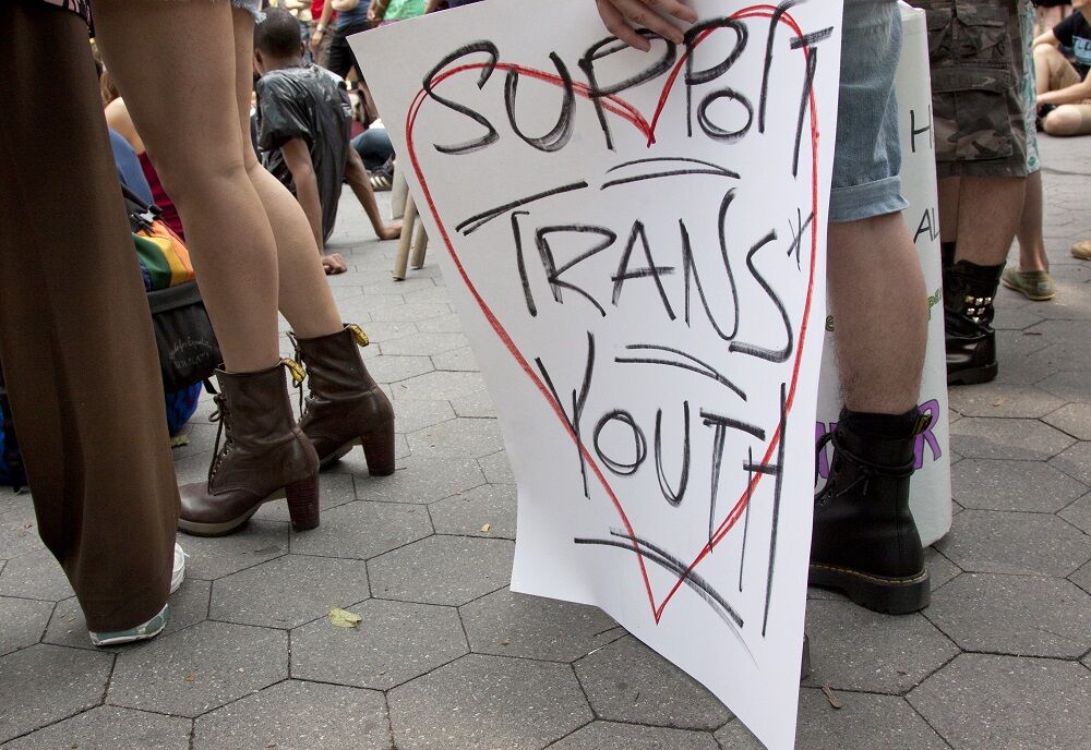 : A supporter holds a sign that says "Support Trans Youth"