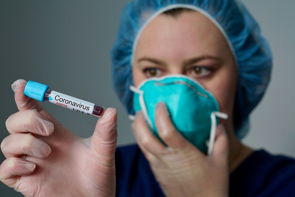 A doctor with a mask holding a vial labeled "coronavirus"
