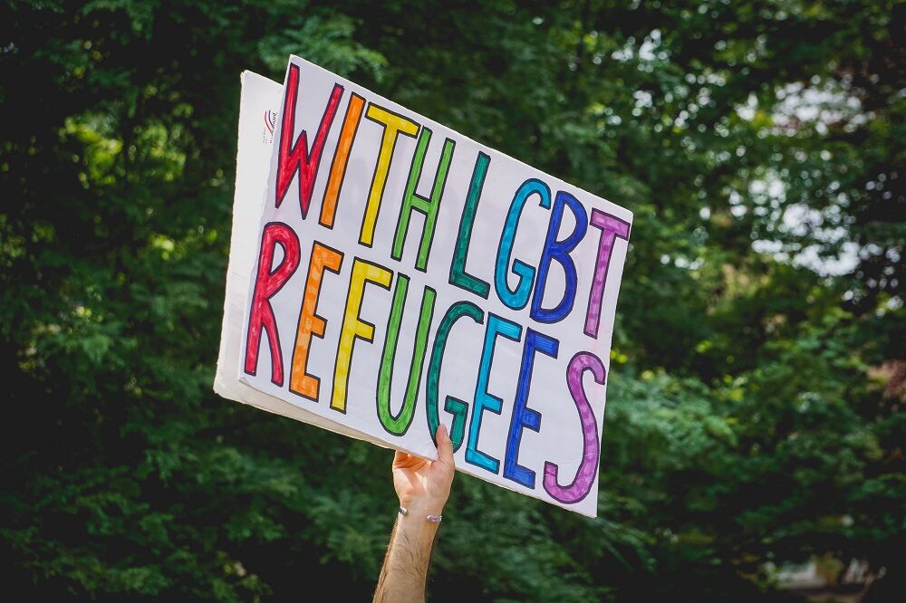 JUNE 30, 2018: An activist in Detroit holds a protest sign that says "With LGBT Refugees."