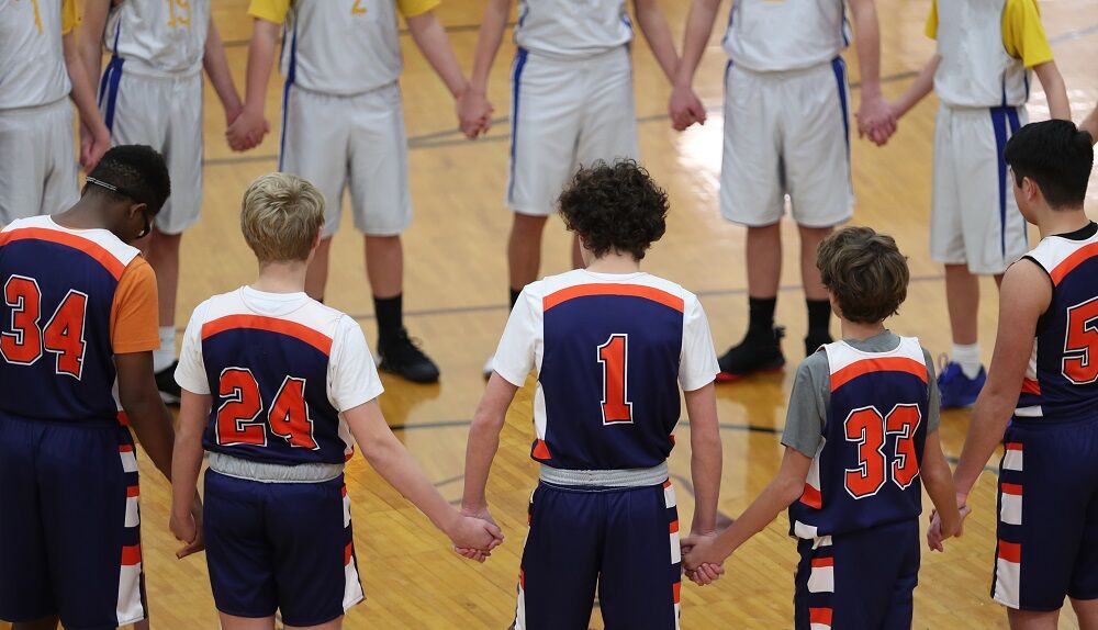 Teens hold hands in prayer before a basketball game