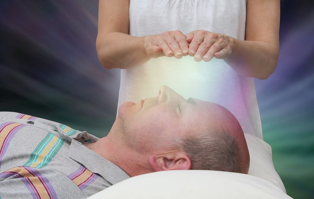 A man being faith-healed by a woman's hands. Faith healing is represented by a white light. It's a stock image.