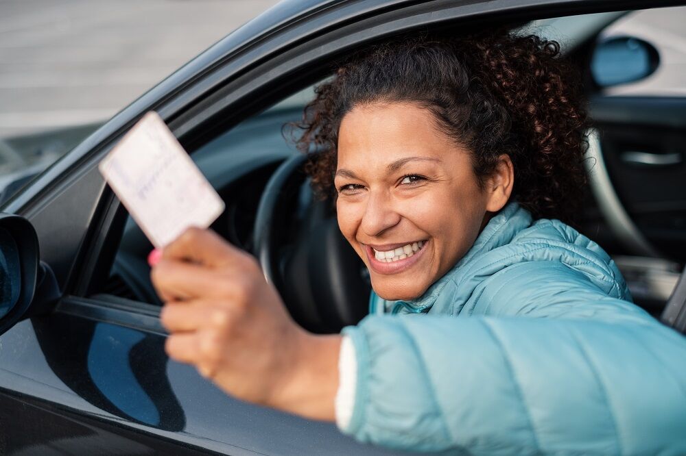 A woman with a drivers license. She's smiling, perhaps because her license has the correct gender marker on it.