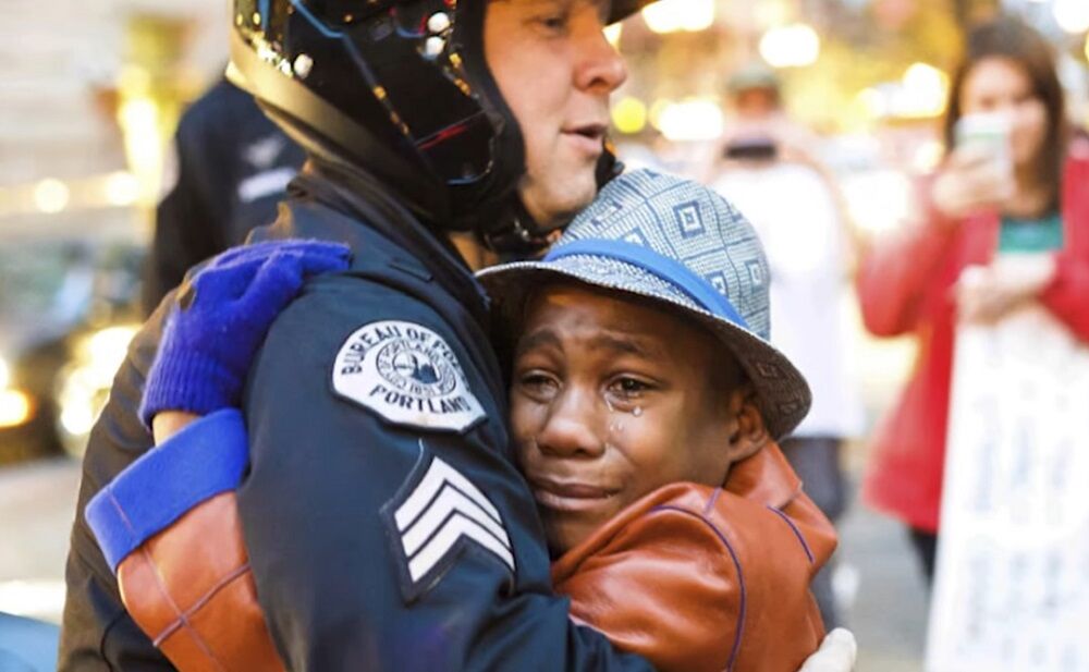 Still of Devonte Hart hugging a cop at a protest