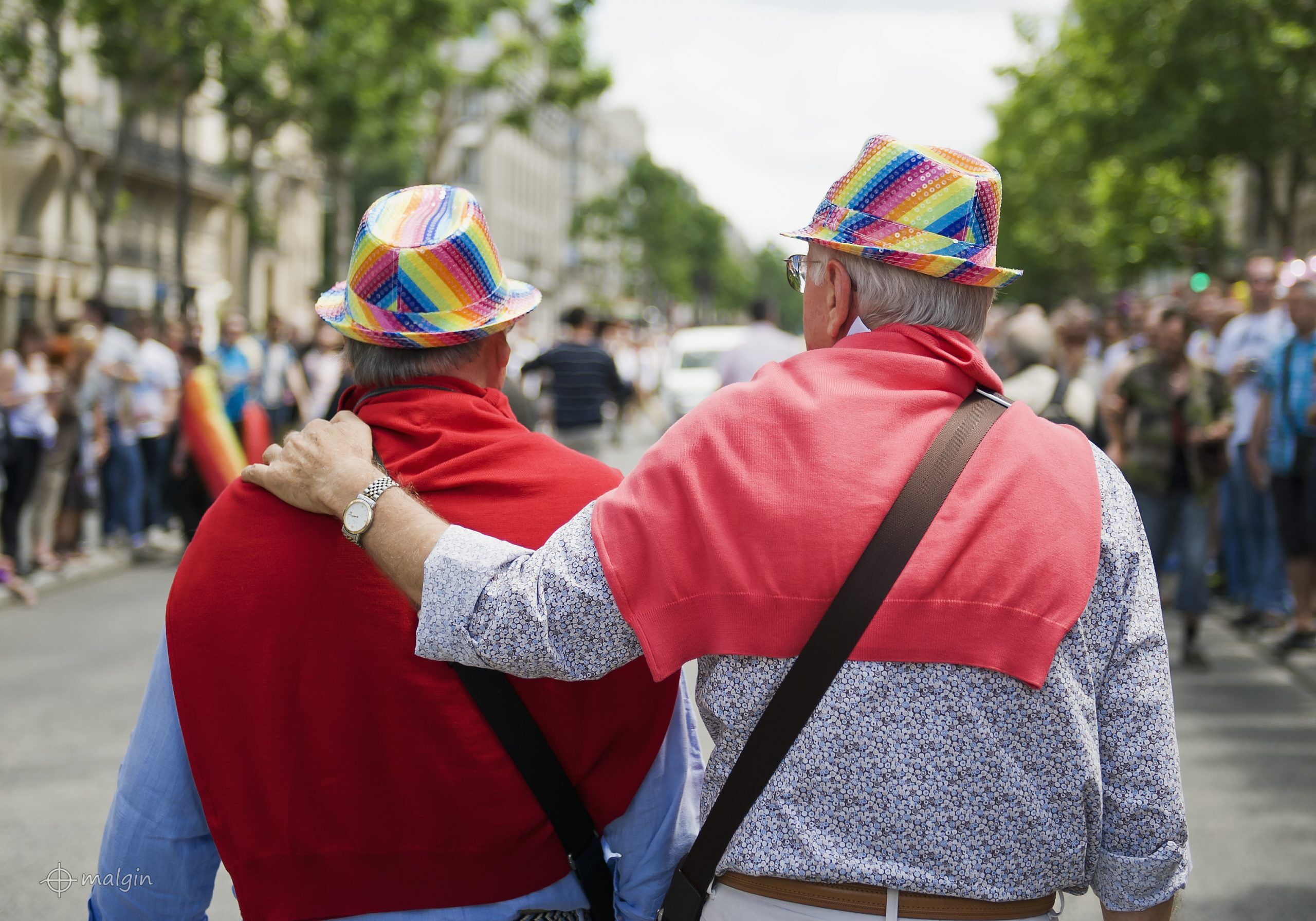 An elderly gay couple in rainbow hats