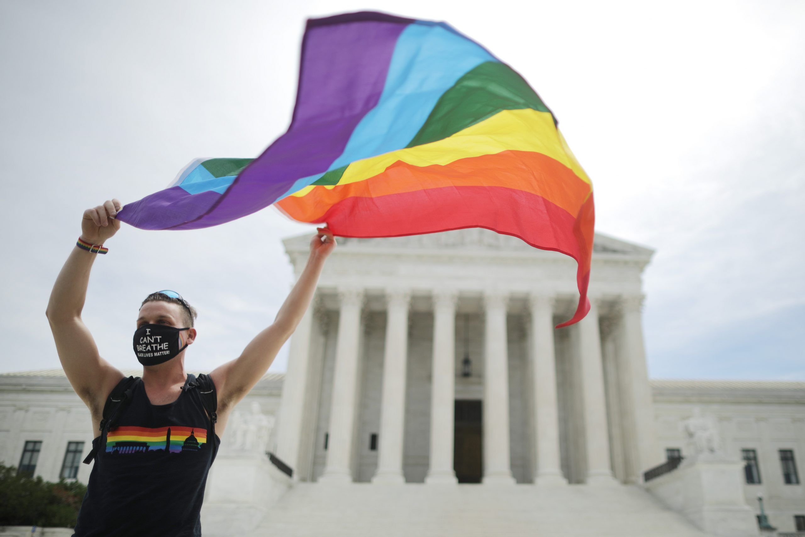 WASHINGTON, DC - JUNE 15: Joseph Fons holding a Pride Flag in front of the U.S. Supreme Court building after the court ruled that LGBTQ people can not be disciplined or fired based on their sexual orientation, Washington, DC, June 15, 2020. With Chief Justice John Roberts and Justice Neil Gorsuch joining the Democratic appointees, the court ruled 6-3 that the Civil Rights Act of 1964 bans bias based on sexual orientation or gender identity. Fons is wearing a Black Lives Matter mask with the words 'I Can't Breathe', as a precaution against COVID-19.