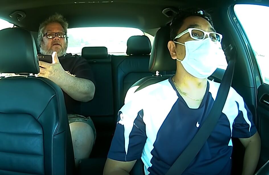 Edgar, wearing a mask, with Richard in the back of the car