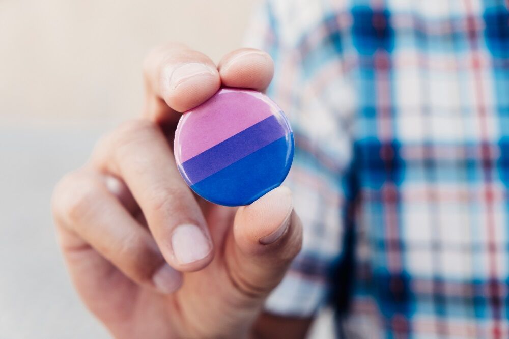 A man holding a pin with the bisexual pride flag on it