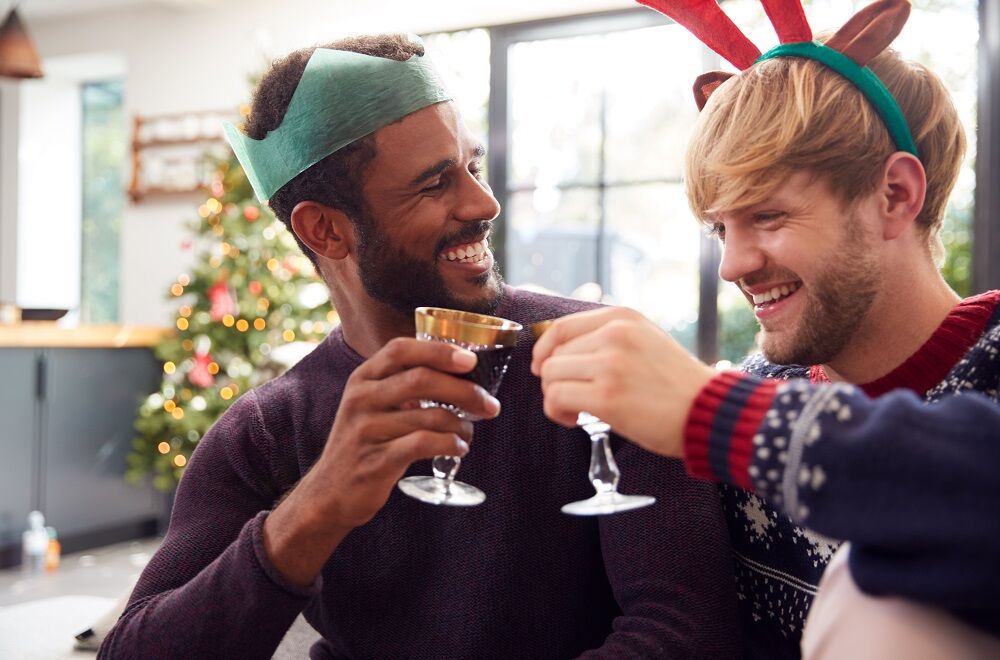 Two men dressed in Christmas attire share wine and they look like a couple. The image is not from the film.