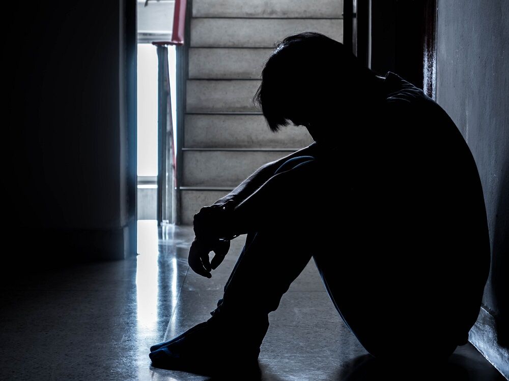 A teen sitting sad on the floor