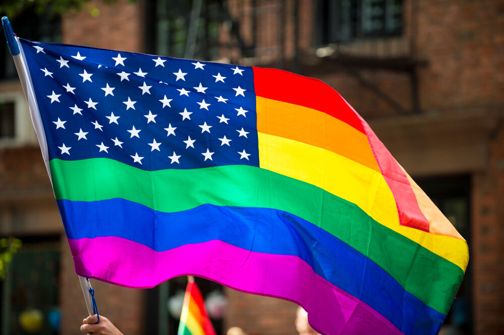 American flag with stars and gay pride rainbow stripes being waved at the annual Gay Pride Parade in Greenwich Village, NYC
