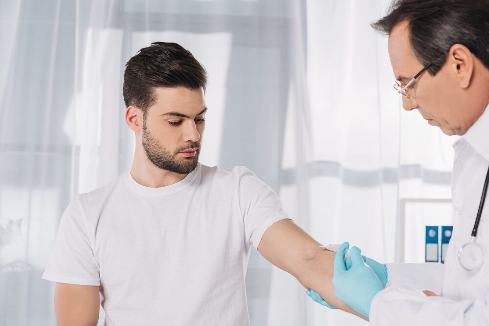 A doctor drawing blood from a patient who spent hours doing his hair just to go to the doctor, apparently