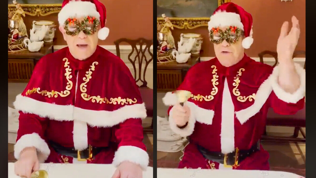 Elton John in his Santa costume, ringing jingle bell and glasses made of wreaths.