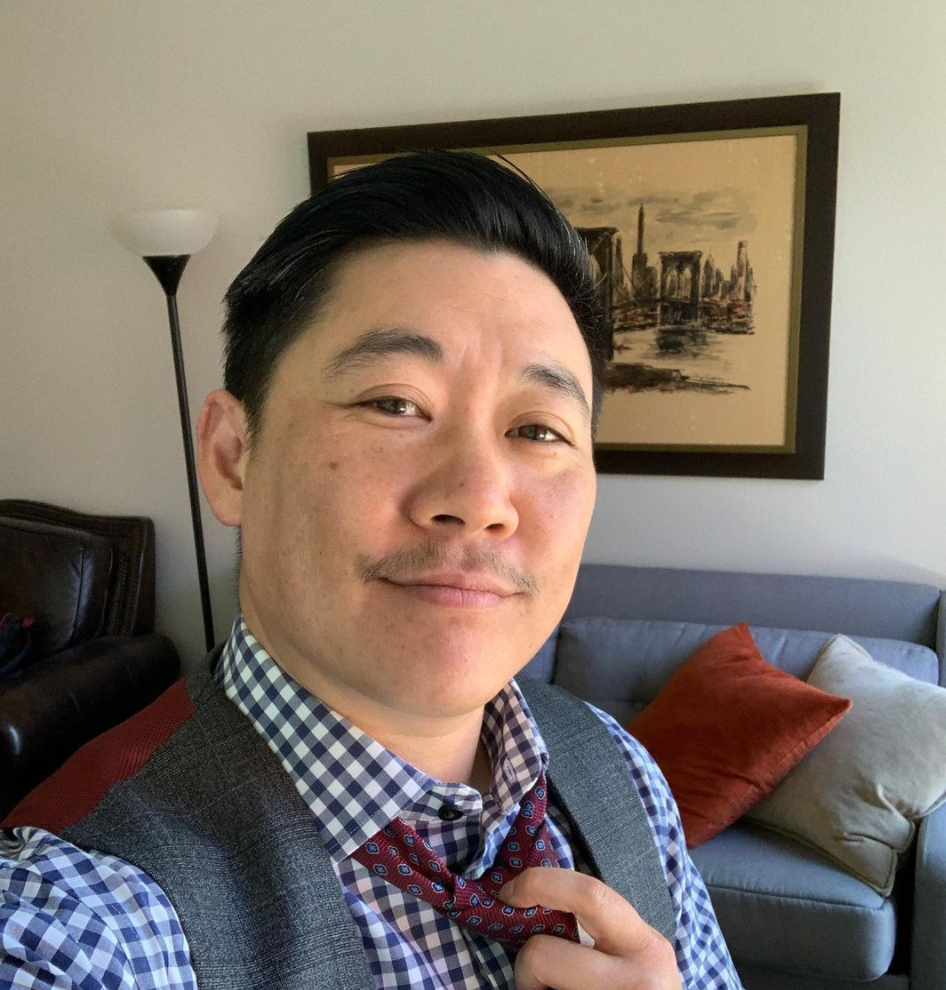 CEO of Sharpe Suiting, Leon Wu, poses in a blue, gray and red suit in his apartment.