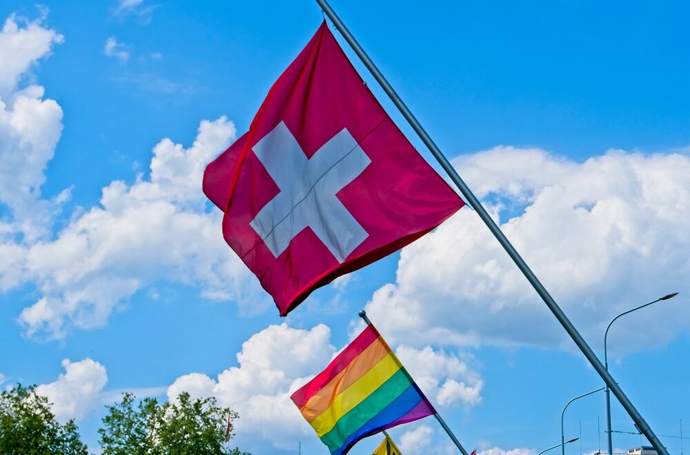 Swiss and rainbow flags fly on a bridge in Geneva