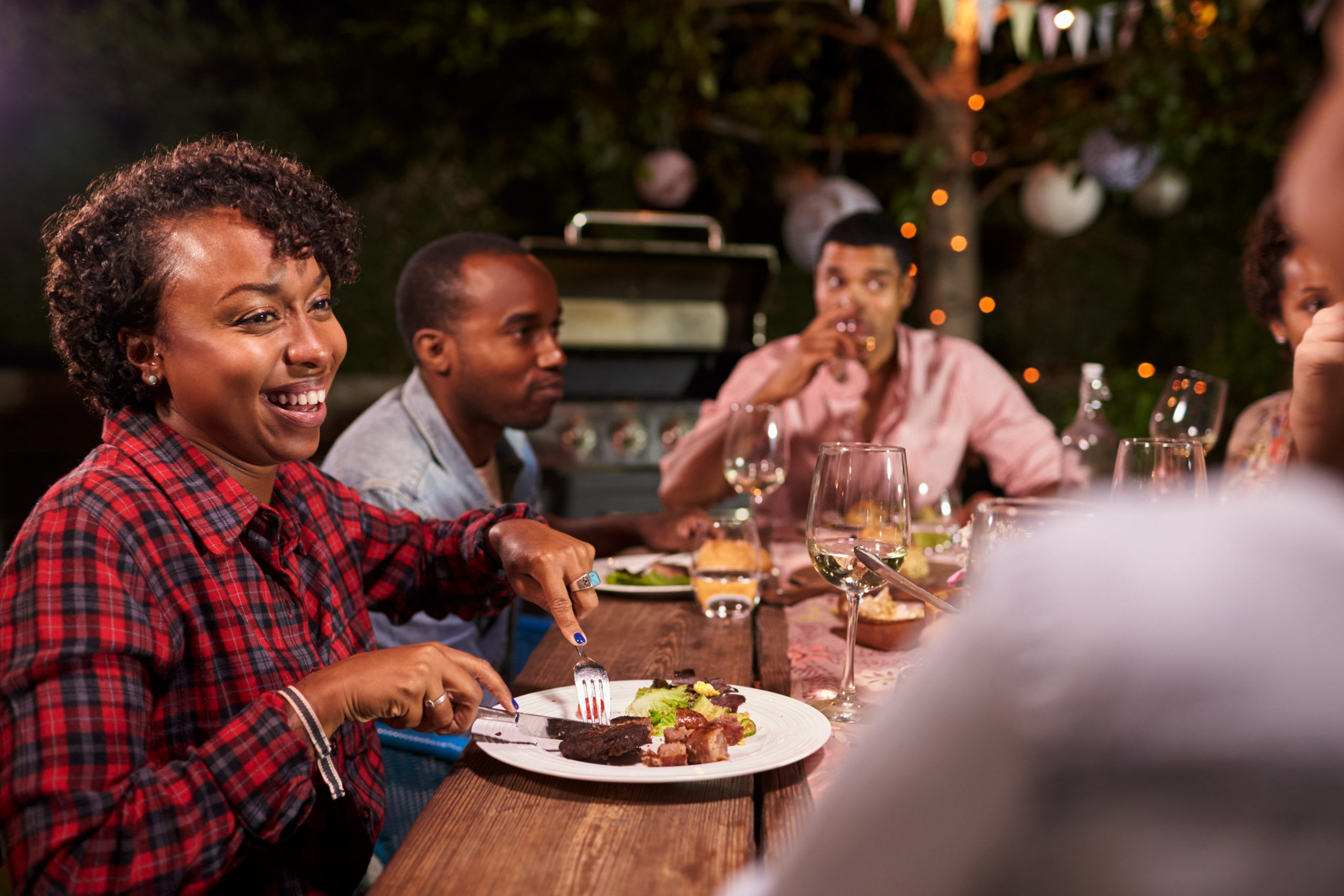 Black Adults enjoying dinner and conversation in garden