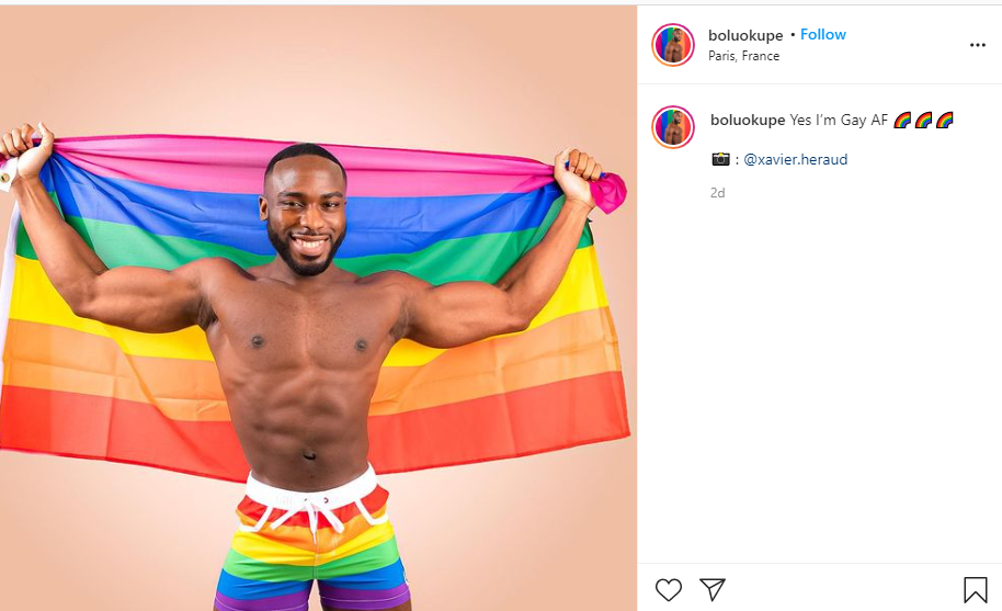 A screenshot of Bolu Okupe's Instagram post proudly stating he's "Gay AF," with a photo of Okupe only in Pride shorts holding a Pride flag as taken by Xavier Héraud