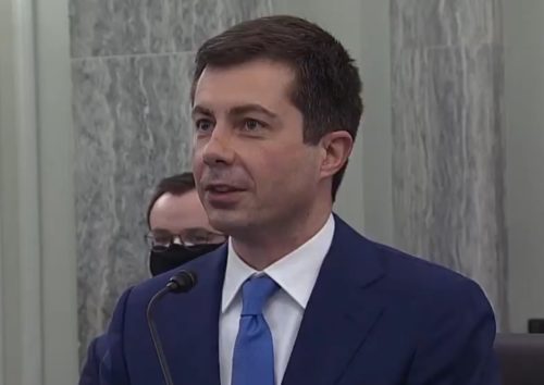 Pete Buttigieg at the Senate confirmation hearing with his husband Chasten behind him